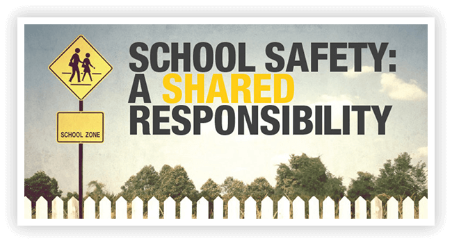 A school safety sign with trees in the background.