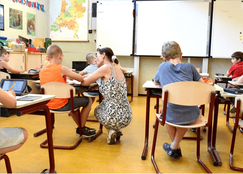 A woman kneeling down in front of two children.