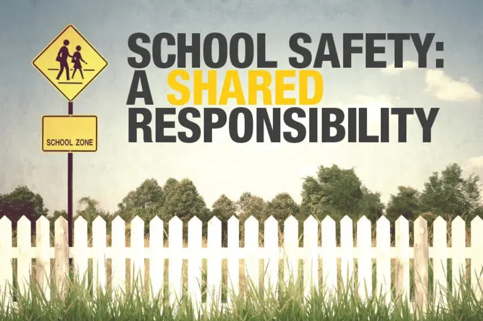 A school safety sign is shown in front of a fence.