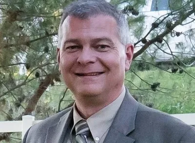 A man in a suit and tie smiling for the camera.