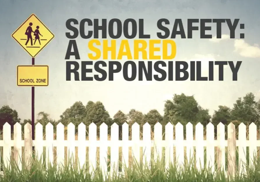 A school safety sign is shown in front of a fence.